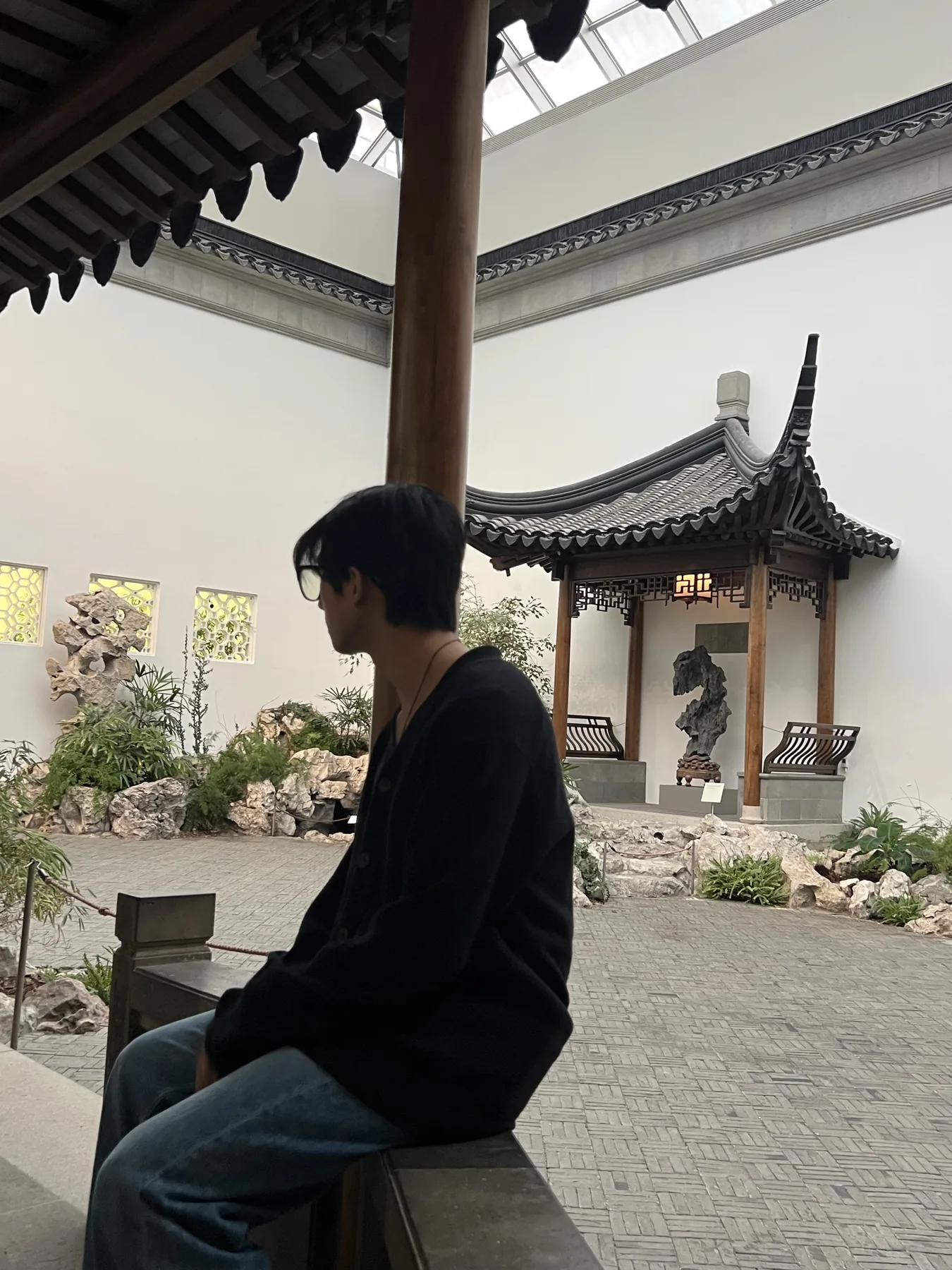 Chris sitting in a covered garden courtyard with traditional pavilion architecture in the background