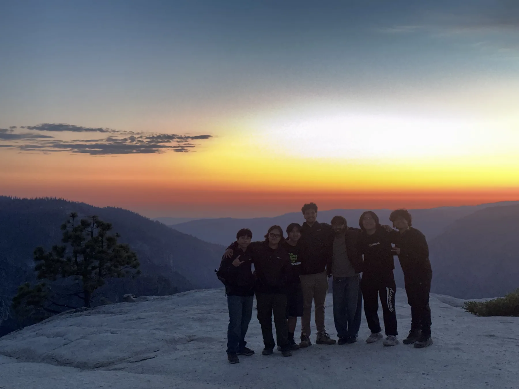 Chris and a group of friends standing together on a rocky overlook at sunset