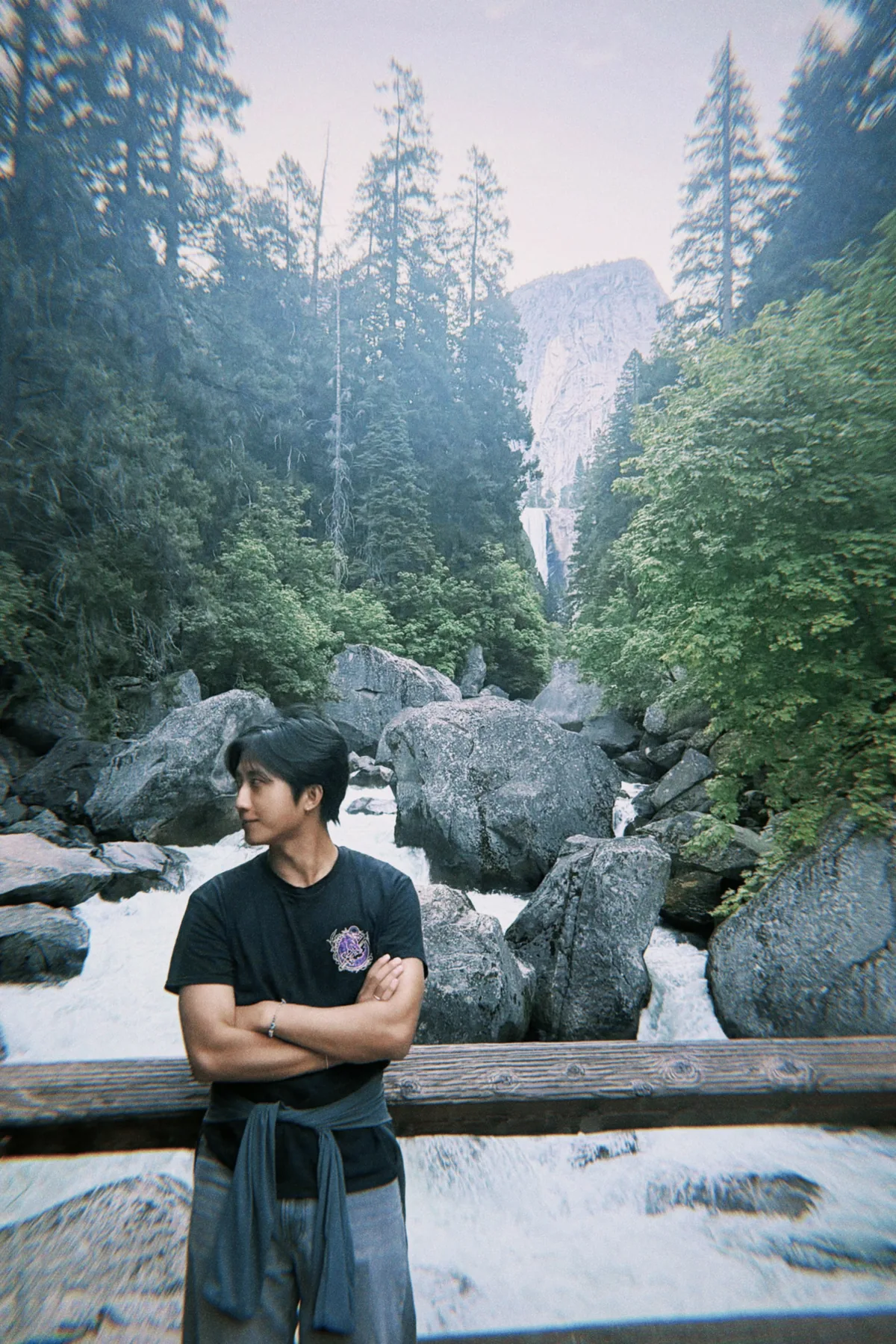 Chris standing near a river in Yosemite with cliffs and a waterfall in the background