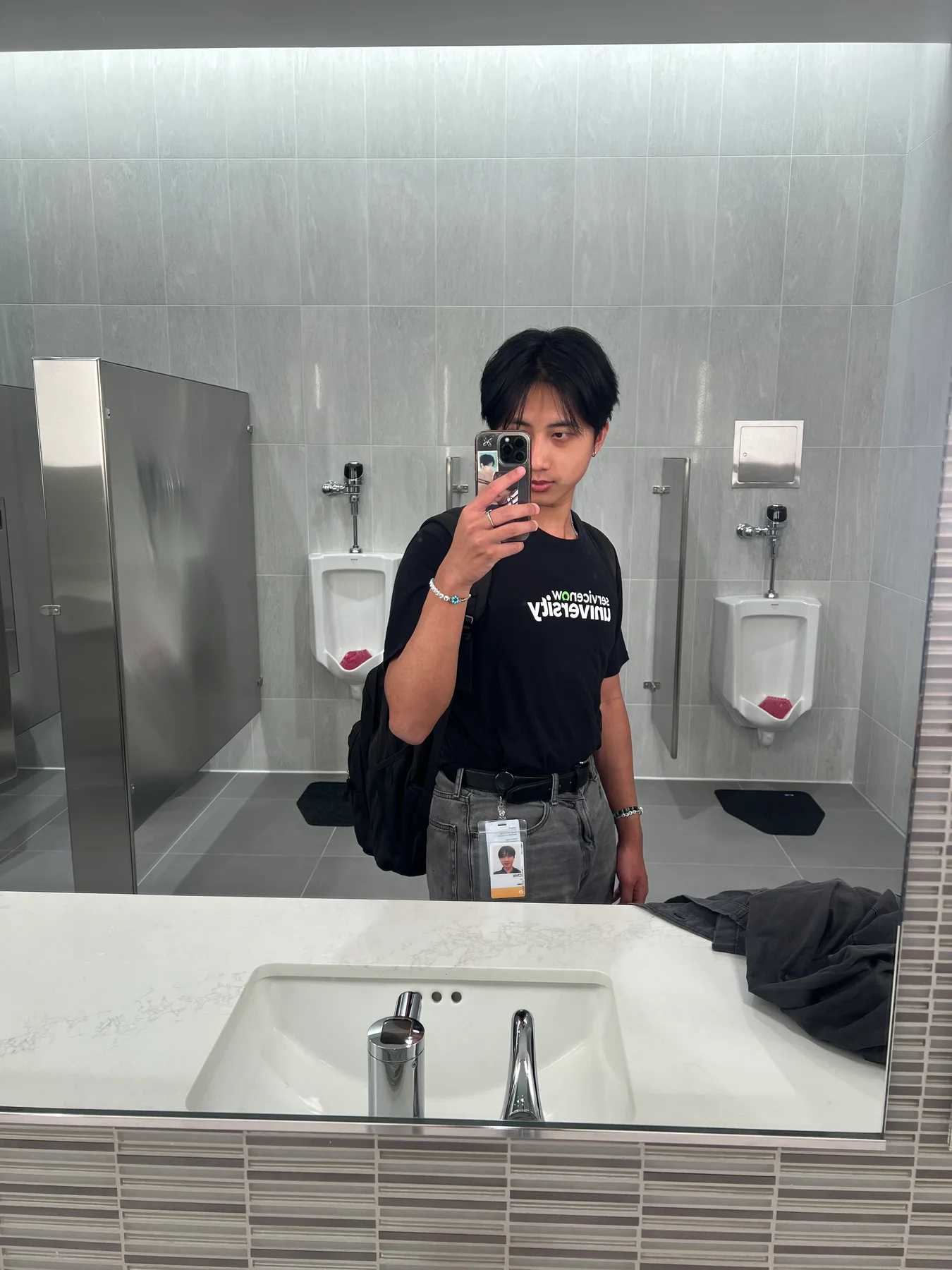 Chris taking a mirror photo while wearing an internship badge